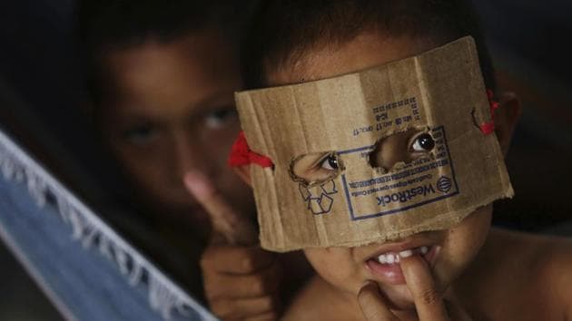 A Warao boy from Venezuela dons a mask fashioned from cardboard at a a shelter in Pacaraima, the main entry point for Venezuelans in the Brazilian state of Roraima. (Eraldo Peres / AP)