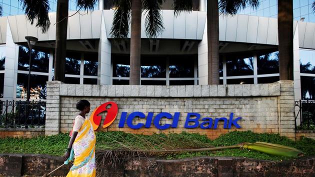 File photo of a municipal worker walking past a logo of ICICI Bank at its headquarters in Mumbai.(Reuters photo)