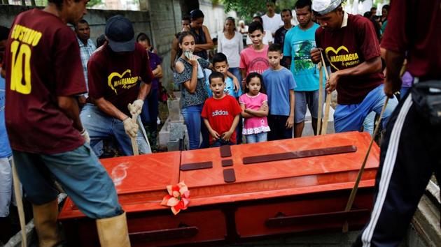 Relatives of Javier Rivas, one of the inmates who died during a riot and fire in the cells of the General Command of the Carabobo Police, react in front of his coffin during his funeral in Valencia, Venezuela. (Carlos Garcia Rawlins / REUTERS)