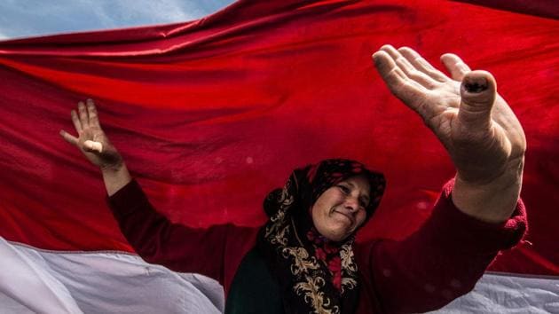 An Egyptian woman dances before a large national flag in Cairo's northern suburb of Shubra al-Khaymah on the second day of voting in the 2018 presidential elections. (Khaled Desouki / AFP)