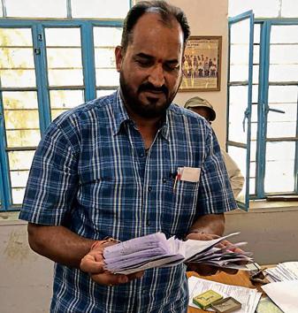 Prof Chandra Shekhar Sharma, head of an anti-copying flying squad of Udaipur’s Mohanlal Sukhadia University, with 128 cheat sheets of printed answers .(HT Photo)