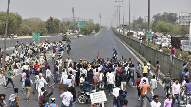 Police and protestors seen at a blockade by protestors on NH 48. Two protesters were killed in police firing in Gwalior during demonstrations. Eighteen people were injured. Parts of Gwalior are under curfew. Earlier, one person was killed and 12 others injured in clashes in Morena town of the state. (Sanjeev Verma / HT Photo)