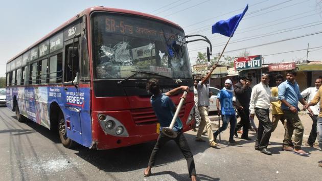 A protester vandalises a public bus during a demonstration by Dalit organisations as part of a countrywide strike against the Supreme Court’s order of diluting the Scheduled Castes and Scheduled Tribes (Prevention of Atrocities) Act, in Bhopal, Madhya Pradesh. 5 people have been killed during violence in the state with another person killed in Rajasthan. (Mujeeb Faruqui/HT Photo)