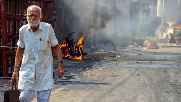 Protestors hurl brickbats as smoke billows from burning cars during Bharat Bandh over the alleged dilution of Scheduled Castes/Scheduled Tribes Act in Muzzaffarnagar in Uttar Pradesh on Monday.(PTI Photo) Protestors hurl brickbats as smoke billows from burning cars during Bharat Bandh over the alleged dilution of Scheduled Castes/Scheduled Tribes Act in Muzzaffarnagar in Uttar Pradesh on Monday.(PTI Photo)