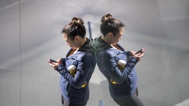 A customer checks her iPhone smartphone store during the sales launch of the Apple Inc. Much more research is obviously needed before we conclude that social media is like tobacco. And even if it is, the harm would need to be very substantial in order to get government policy involved in limiting social-media use.(Bloomberg via Getty Images)