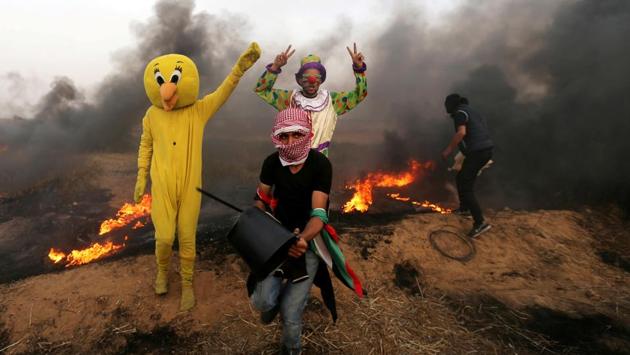 Palestinians wearing costumes are seen at the site of clashes along the Israel-Gaza border in the southern Gaza Strip. (Ibraheem Abu Mustafa / REUTERS)