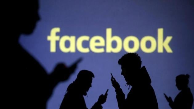 Silhouettes of mobile users next to a screen projection of Facebook logo in a picture illustration, March 28, 2018.(REUTERS)