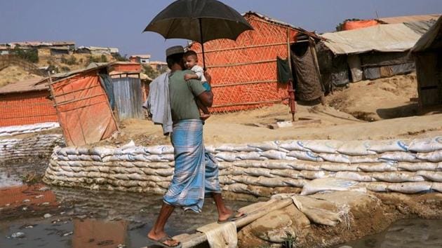 A Rohingya refugee carries his child across a bamboo bridge in Balukhali refugee camp, in Cox's Bazar, Bangladesh.(Reuters)