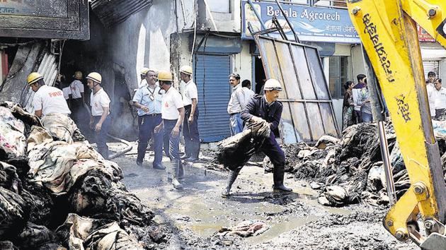 Firefighters move gunny bags gutted during the fire at a wholesale grain godown on Monday at Market Yard. No casualties were reported from the incident. (Rahul Raut/HT PHOTO)