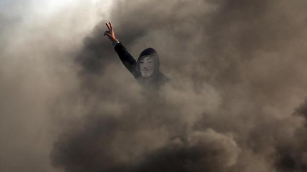 A Palestinian protester flashes the victory sign near the Gaza Strip border with Israel. For some of the young men hanging around the camp, the chant wasn’t just rousing hyperbole. They have been throwing stones and burning tires near the border, despite new warnings by Israel’s defense minister that anyone getting too close to the fence risks getting killed. (Khalil Hamra / AP) A Palestinian protester flashes the victory sign near the Gaza Strip border with Israel. For some of the young men hanging around the camp, the chant wasn’t just rousing hyperbole. They have been throwing stones and burning tires near the border, despite new warnings by Israel’s defense minister that anyone getting too close to the fence risks getting killed. (Khalil Hamra / AP)