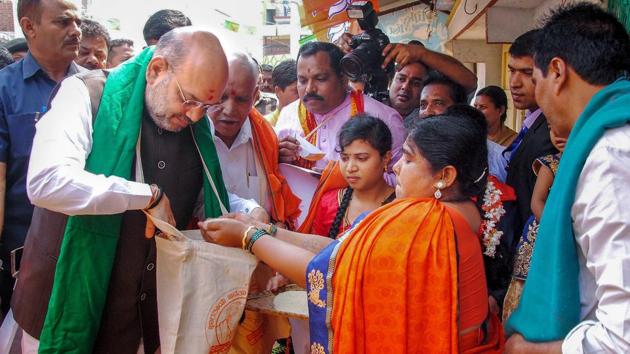 Bharatiya Janata Party chief Amit Shah collects foodgrains from a farmer family during a statewide door-to-door campaign, ahead of the Karnataka assembly elections at Doddabathi village in Davanagere on March 27.(PTI file photo)