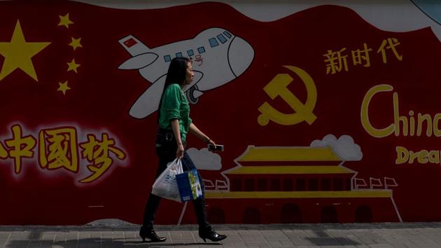 A woman passes a wall mural which reads ‘China Dream’ in Shanghai on April 11, 2018.(AFP)