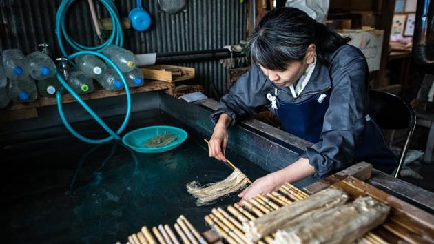 Karumi Nakano runs the now soft and pliant kozo fibers in pure running water one last time to remove lye residue and untangle individual fibers as they near the stage of becoming paper. Any minerals or impurities in the water at this stage can ruin the paper quality. (Carl Court / Getty Images)