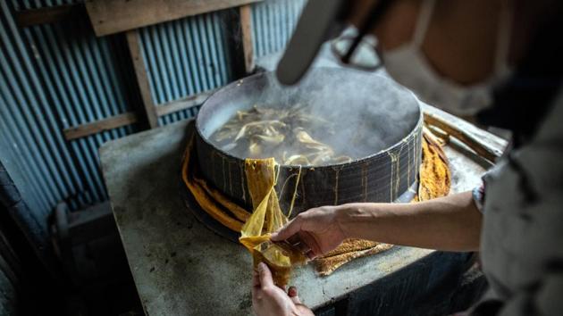 Once scraped, the bark is boiled in water to separate fiber and impurities, rinsed and dried. A second boiling in lye breaks fibers down and rids them of starch and tannin. Ichimura is seen here checking the consistency of the bark as it boils. (Carl court / Getty Images)