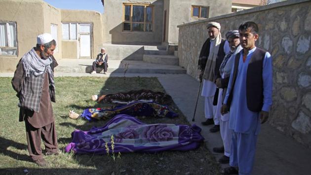 People stand near the bodies of district officials inside the Khuja Omari district compound after a deadly attack in Ghazni, Afghanistan, Thursday, April 12, 2018.(AP Photo)