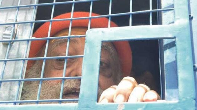 Asaram looks out from the police van while on way to attend the hearing in a court in Jodhpur.(HT File)