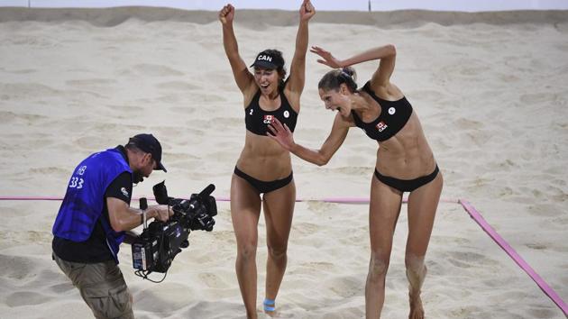 Canada's Melissa Humana-Paredes (C) and Sarah Pavan (R) celebrate winning the gold medal in the women's beach volleyball final against Australia on April 12, 2018. (William West / AFP)