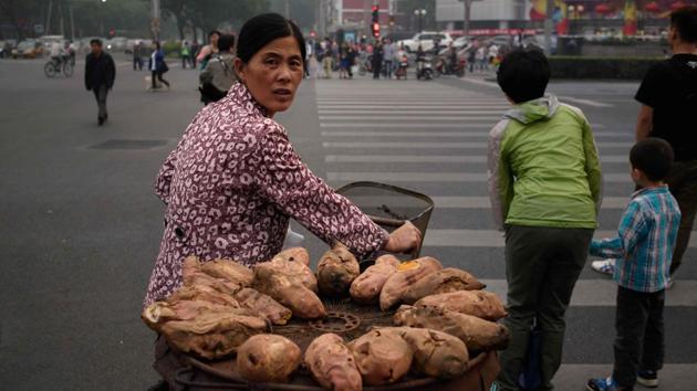 A sweet potato vendor waits to cross a street in Beijing. The bulbous, colourful sweet potato has long been seen as an artifact of mankind's first ocean voyages, ferried from its home in South America all the way to Polynesia centuries ago.(AFP) A sweet potato vendor waits to cross a street in Beijing. The bulbous, colourful sweet potato has long been seen as an artifact of mankind's first ocean voyages, ferried from its home in South America all the way to Polynesia centuries ago.(AFP)