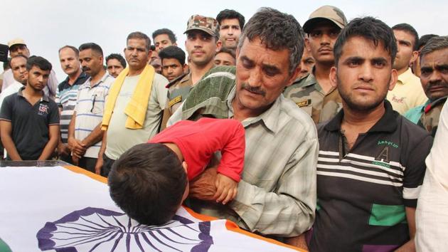 Father and son of Jaki Sharma, who was killed along the LoC in shelling from Pakistan side, pay tribute to him during his funeral at his native village Sanyal in Hiranagar, Jammu on April 10, 2018. (PTI) Father and son of Jaki Sharma, who was killed along the LoC in shelling from Pakistan side, pay tribute to him during his funeral at his native village Sanyal in Hiranagar, Jammu on April 10, 2018. (PTI)