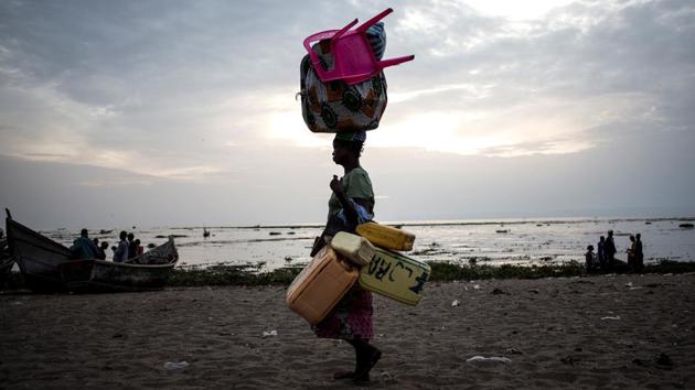 A displaced Congolese woman walks with her belongings along the shore line of Lake Albert after spending the night out by the lake for safety. Congo is also dealing with its worst cholera outbreak in decades, which killed more than 1,000 people last year. As of last month, cases in the capital Kinshasa were declining but the situation remained alarming. (John Wessels / AFP)
