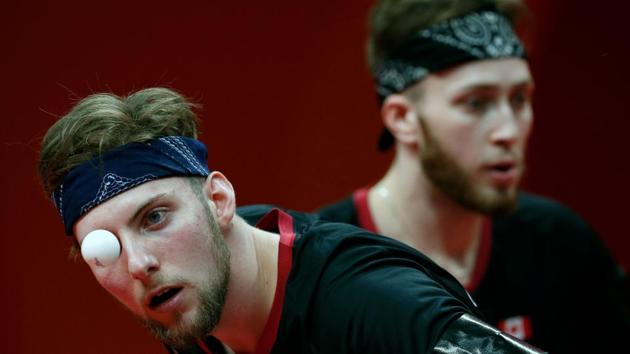 Canada's Marko Medjugoracz (L) serves alongside partner Antoine Bernadet during the men’s team quarter-final table tennis match against Singapore at the Oxenford Studios venue on April 7, 2018. (Adrian Dennis / AFP)