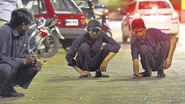 Automobile mechanics near Shaniwarwada , unfazed by the traffic, take their marble ­playing skills to the streets on April 10. (Pratham Gokhale/HT Photo) 