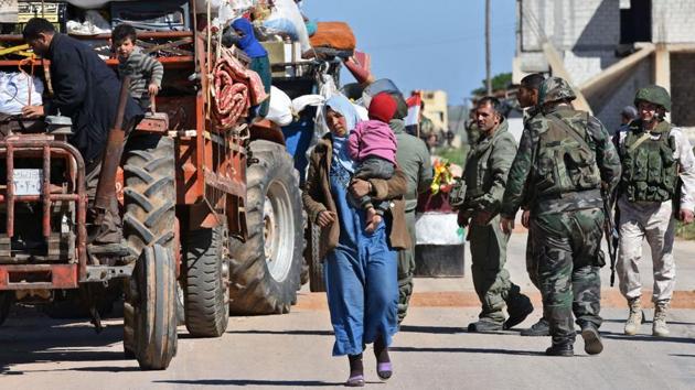 Displaced Syrian families arrive at a checkpoint manned by Syrian soldiers and Russian forces allied with the Syrian regime at the Abu al-Duhur crossing, as they return from rebel-held areas in Syria's northern Idlib province to their villages in government controlled territory in Idlib on April 4, 2018.(AFP)