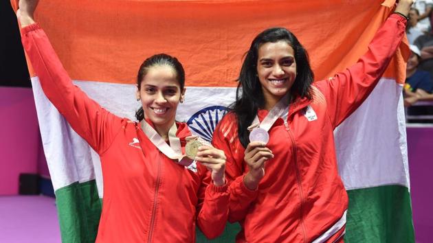 Women's singles gold medallist Saina Nehwal and silver medallist PV Sindhu pose with the tricolour at the 2018 Commonwealth Games in Gold Coast on Sunday.(PTI)