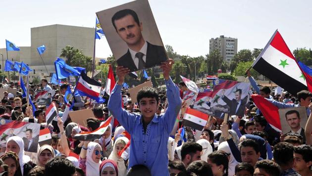 In this photo released by the Syrian official news agency SANA, protesters wave flags and portraits of President Bashar Assad, as they march during a demonstration to show solidarity with the Syrian armed forces, at Omayyad Square, in Damascus, Syria, Monday, April 16, 2018.(AP)