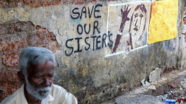 A man sits next to a graffiti which depicts a message in protest against the Kathua case, in Kochi on April 16, 2018. (Sivaram V / REUTERS) 