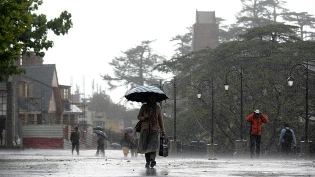 People take a stroll during the wind storm and rain at Ridge on Friday evening, in Shimla. (Deepak Sansta/HT)