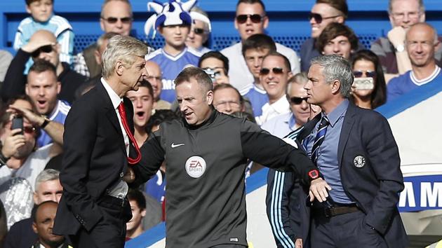 In this file photo taken on October 05, 2014 Chelsea's Portuguese manager Jose Mourinho (R) and Arsenal's French manager Arsene Wenger (L) are kept apart by the fourth official Jonathan Moss during the English Premier League football match. (AFP) 