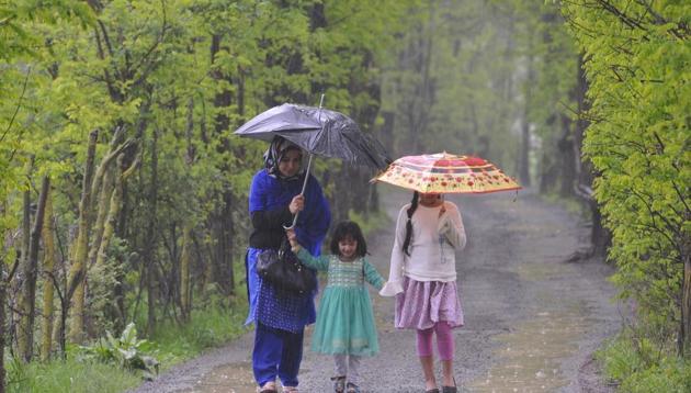 A Kashmiri woman walks along with her children as it rains in Srinagar on Friday. The minimum temperature was 8.6 degrees Celsius in Srinagar. (Waseem Andrabi /HT)