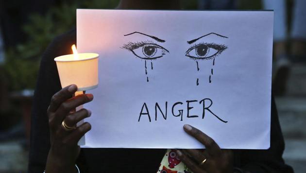 A woman holds a candle and placard during a protest against sexual violence. A Class 6 students was allegedly abducted and raped in Odisha, police said.(AP File Photo)