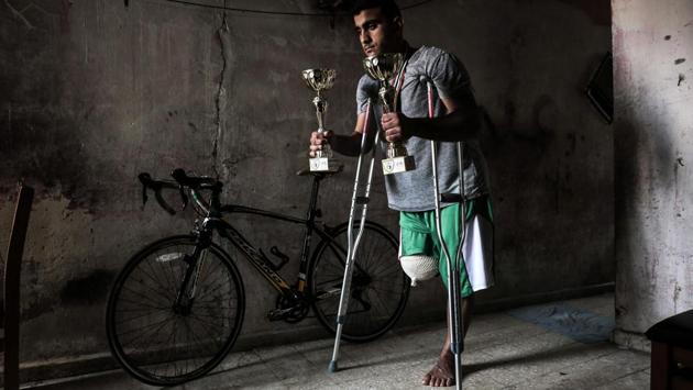Palestinian cyclist Alaa Al-Daly, 21, who lost his leg by a bullet fired by Israeli troops along the Gaza border during a protest, stands next to his bicycle holding trophies he has won in competitions, at his home in Rafah in the southern Gaza Strip on April 19, 2018. (Said Khatib / AFP)