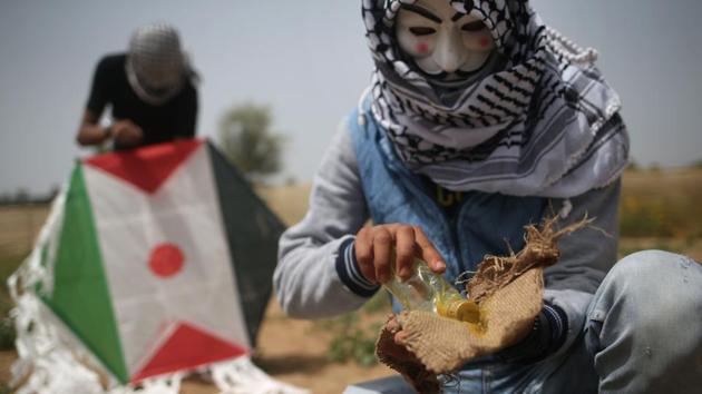 Palestinians prepare an incendiary device to be attached to a kite before trying to fly it over the border fence with Israel in a new tactic as demonstrations enter their fourth week, on the eastern outskirts of Gaza City on April 20, 2018. (Mohammed Abed / AFP)