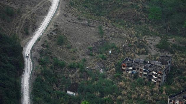 A vehicle drives past apartment blocks destroyed in a landslide caused by the 2008 earthquake, at the foot of a mountain. The 7.9 magnitude quake which hit on May 12, 2008 was most devastating around its epicentre in Beichuan. Many of the houses that collapsed remain buried under the earth and are covered by overgrown bushes and weeds. (Jason Lee / REUTERS)