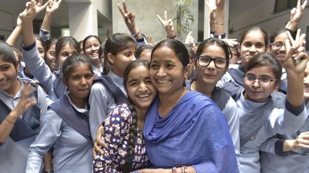 Pooja Joshi (centre) gets a huig from her mother as fellow students cheer after PSEB results in Ludhiana on Monday. (Gurpreet Singh/HT)