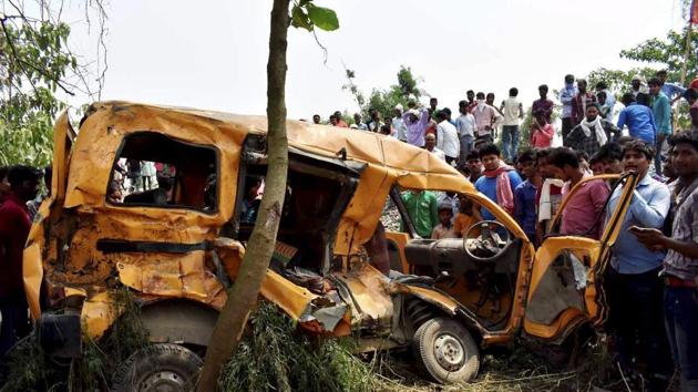 People gather around the mangled school van which collided with a moving train in Kushinagar on Thursday.(PTI Photo)