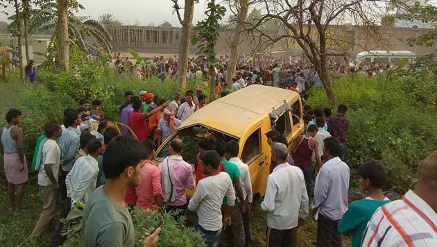 People gather around the mangled school van after it collided with a moving train in Kushinagar, Uttar Pradesh, on Thursday morning.(PTI Photo)