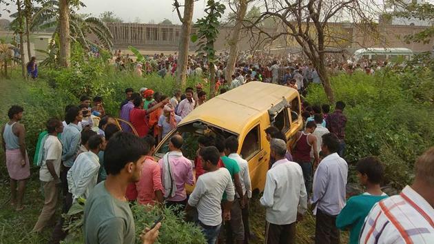 People gather around the mangled school van after it collided with a moving train in Kushinagar, Uttar Pradesh, on Thursday morning.(PTI)
