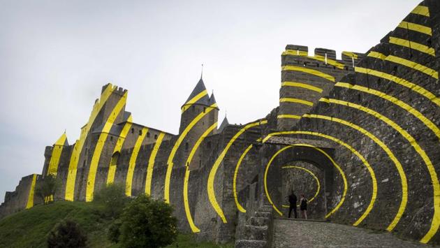 Tourists visit the medieval city of Carcassonne, whose walls are partly covered with yellow concentric circles created by the Paris-based, Swiss artist Felice Varini at the request of the National Center for National Monuments to celebrate the twentieth anniversary of the inscription of the city as UNESCO World Heritage. (Eric Cabanis / AFP) Tourists visit the medieval city of Carcassonne, whose walls are partly covered with yellow concentric circles created by the Paris-based, Swiss artist Felice Varini at the request of the National Center for National Monuments to celebrate the twentieth anniversary of the inscription of the city as UNESCO World Heritage. (Eric Cabanis / AFP)
