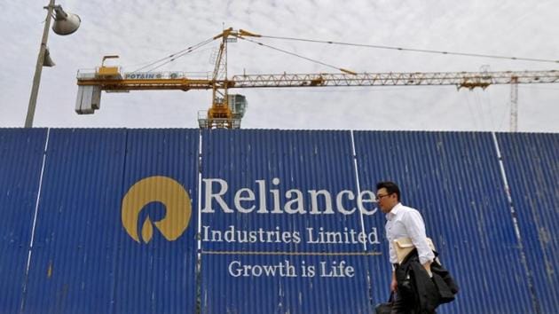 A man walks past an advertisement of Reliance Industries Limited at a construction site in Mumbai.(Reuters File Photo)