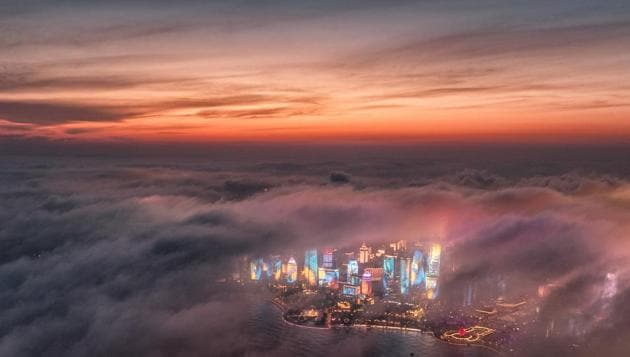 Advection fog drifts across skyscrapers on the waterfront in Qingdao in eastern China's Shandong Province. A weather system brought clouds and rain to parts of China on Saturday. (Lu Hui / Xinhua via AP) Advection fog drifts across skyscrapers on the waterfront in Qingdao in eastern China's Shandong Province. A weather system brought clouds and rain to parts of China on Saturday. (Lu Hui / Xinhua via AP)