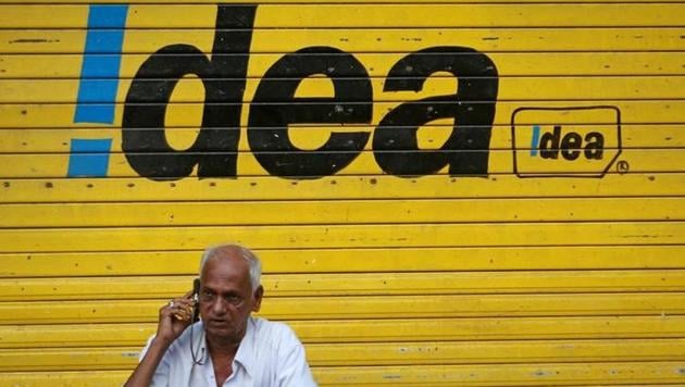 A man speaks on his mobile phone as he sits in front of a shop displaying the Idea Cellular Ltd's logo on its shutter in Mumbai on April 28.(Reuters File)