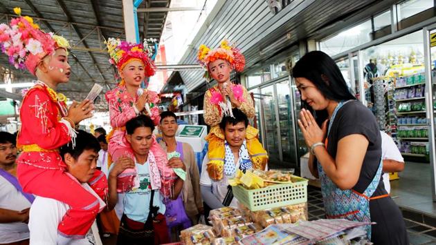 Phuwadol Kong Tawan (L), 11, Gorsak Kong Tawan (C), 13, and Danusorn Sdisaithaworn, 10, pray for a merchant at a market while being carried on shoulders during the annual Poy Sang Long celebration. From this stage until the end of the festival, the boys are believed to have acquired semi-divine status, and are not allowed to touch the ground. (Jorge Silva / REUTERS) 