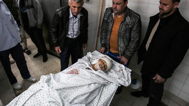 Graphic content / Relatives of 15-year-old Palestinian teenager Azzam Oweida gather around his body in the morgue of a hospital in Khan Yunis in the southern Gaza Strip on April 28, 2018, as he succumbed to his wounds a day after he was shot by Israeli forces in clashes along the Gaza border.(AFP)