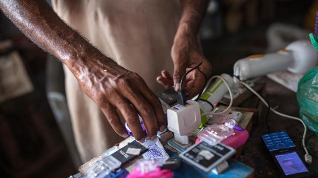 A vendor plugs a smartphone battery into a solar powered charging unit at a grocery store in Sujawal. It’s been a sound investment so far. Dino now makes as much as 3,000 rupees extra each month from customers attracted by the perks. He’d spend more earlier to run a gasoline generator. (Asim Hafeez / Bloomberg) A vendor plugs a smartphone battery into a solar powered charging unit at a grocery store in Sujawal. It’s been a sound investment so far. Dino now makes as much as 3,000 rupees extra each month from customers attracted by the perks. He’d spend more earlier to run a gasoline generator. (Asim Hafeez / Bloomberg)