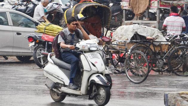 A student makes his way through the rain on a two-wheeler in Amritsar on Wednesday. (Sameer Sehgal/HT)