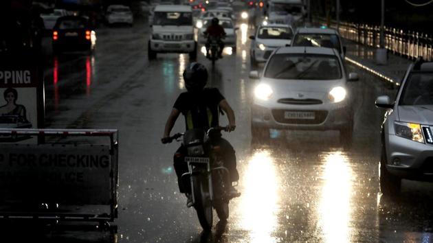 Commuters turn on their vehicle headlights on Wednesday afternoon as the weather turned turtle after storm and rain in Chandigarh. (Keshav Singh/HT)